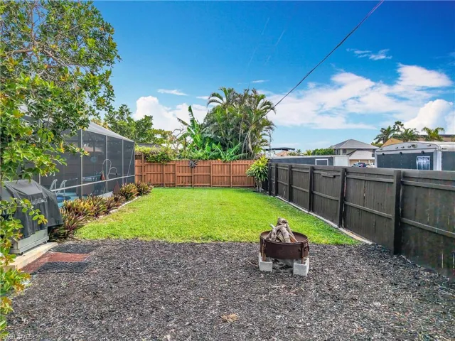 View of yard featuring a lanai, a fenced backyard, and a fire pit