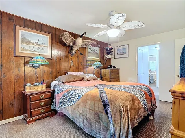 Carpeted bedroom with wood walls and ceiling fan