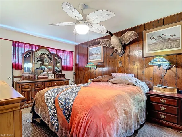 Bedroom featuring wooden walls, a ceiling fan, and carpet flooring