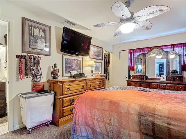 Carpeted bedroom featuring ceiling fan and visible vents
