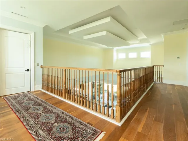 Corridor featuring wood finished floors, ornamental molding, baseboards, and an upstairs landing
