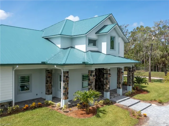View of front of house featuring a front yard, stone siding, metal roof, covered porch, and a standing seam roof