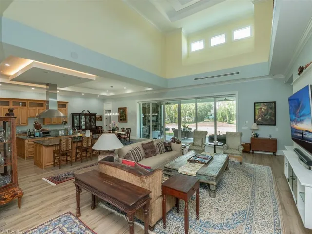 Living room with a towering ceiling, light wood-style flooring, and crown molding