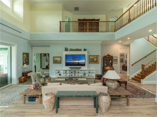 Living room with a towering ceiling, stairs, wood finished floors, ornamental molding, and recessed lighting