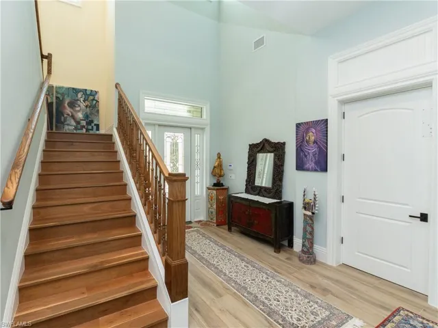 Foyer featuring stairs, light wood-style floors, a towering ceiling, and baseboards
