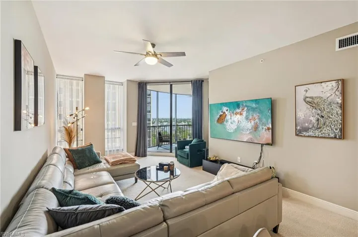 Carpeted living room featuring floor to ceiling windows and ceiling fan