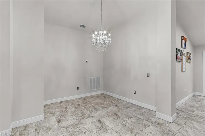 Unfurnished dining area with a chandelier, baseboards, and light marble finish floors