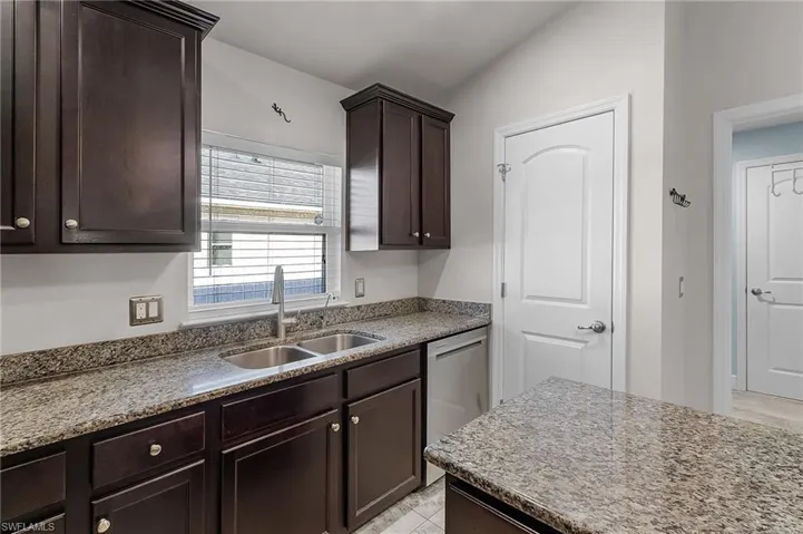 Kitchen with a sink, dishwasher, and dark brown cabinetry