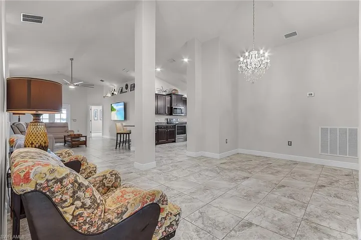Living area with ceiling fan, a chandelier, baseboards, and high vaulted ceiling