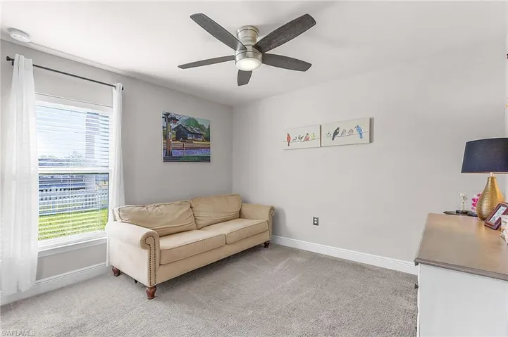 Living area with baseboards, light colored carpet, and ceiling fan