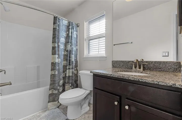 Full bath with toilet, vanity, shower / bath combo with shower curtain, and tile patterned flooring