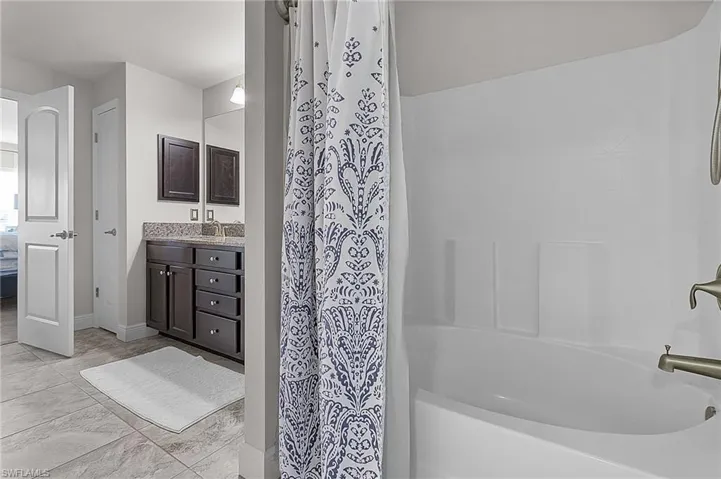 Bathroom with ensuite bath, vanity, baseboards, and shower / bath combination with curtain