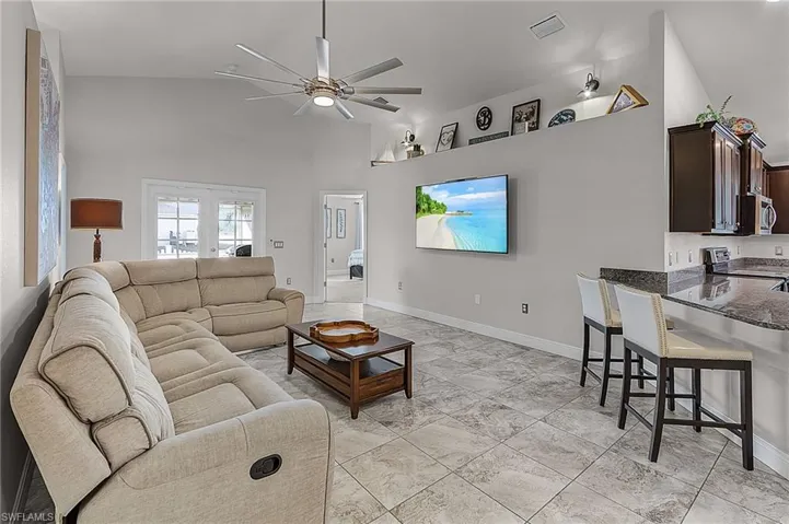 Living area with a ceiling fan, baseboards, and high vaulted ceiling