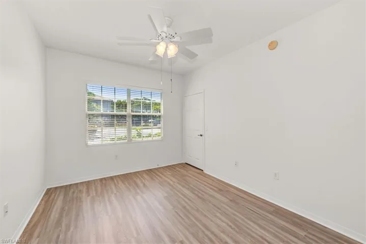 2nd bedroom featuring wood-finish flooring, a ceiling fan with integrated lighting, and a window with horizontal blinds