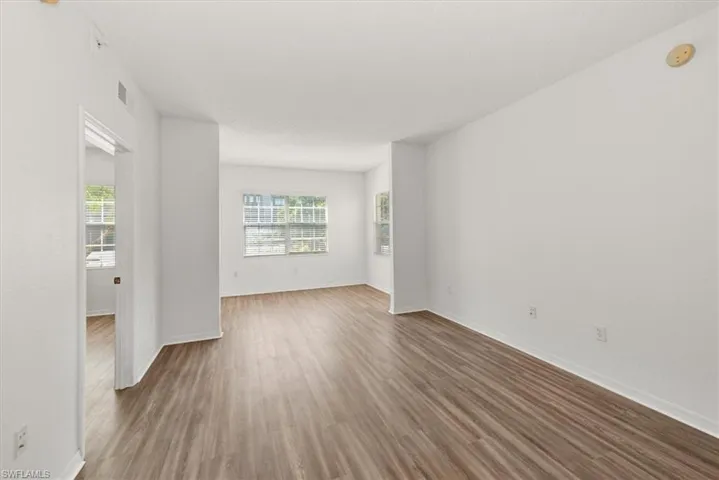 Spacious interior featuring wood-finish flooring, white walls, and multiple windows