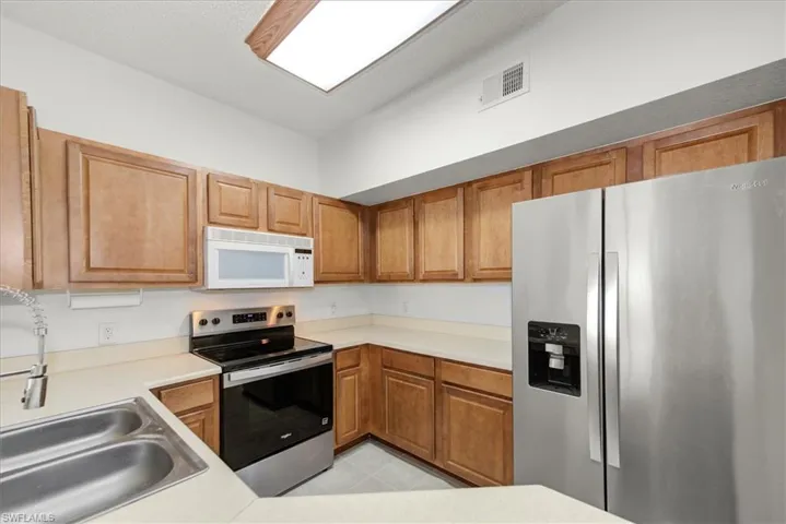 Kitchen featuring wood-finish cabinetry, light-toned countertops, and stainless steel appliances