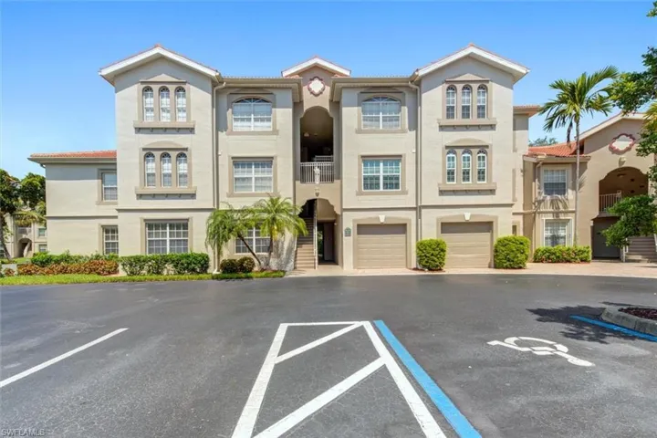 Multi-story stucco exterior featuring a terra cotta tile roof, arched architectural details, integrated single-car garages, and mature tropical landscaping