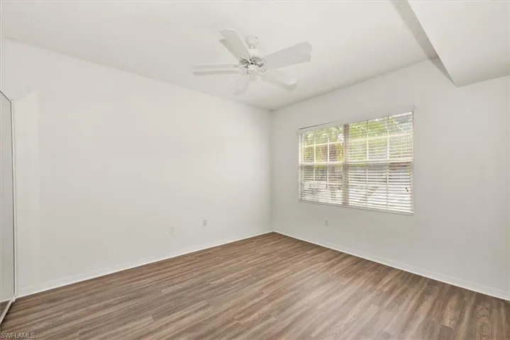 Bright room with wood-finish flooring, a window featuring blinds, a ceiling fan, and white walls