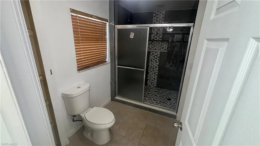 Full bath with a stall shower and light tile patterned flooring
