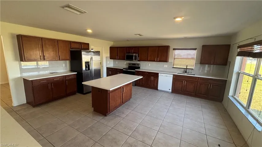 Kitchen featuring light countertops, appliances with stainless steel finishes, light tile patterned flooring, tasteful backsplash, and recessed lighting