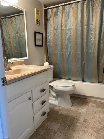 Full bathroom with vanity, toilet, and shower / bath combo with shower curtain