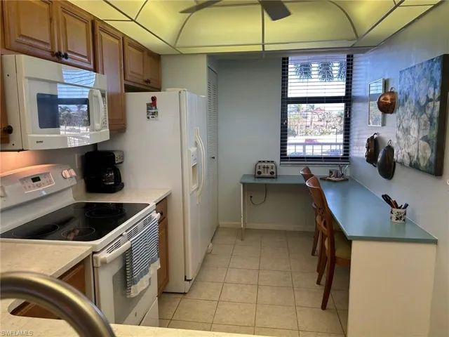 Kitchen with white appliances and light tile patterned flooring