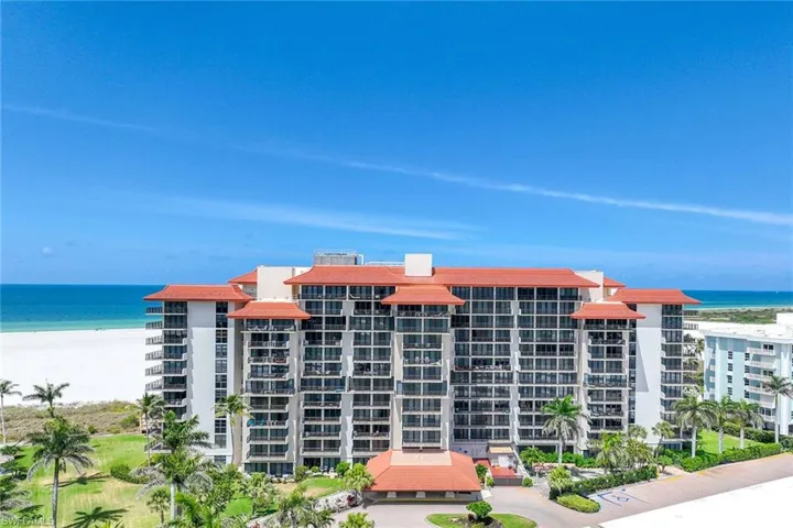 View of apartment building / complex with view of water and beach
