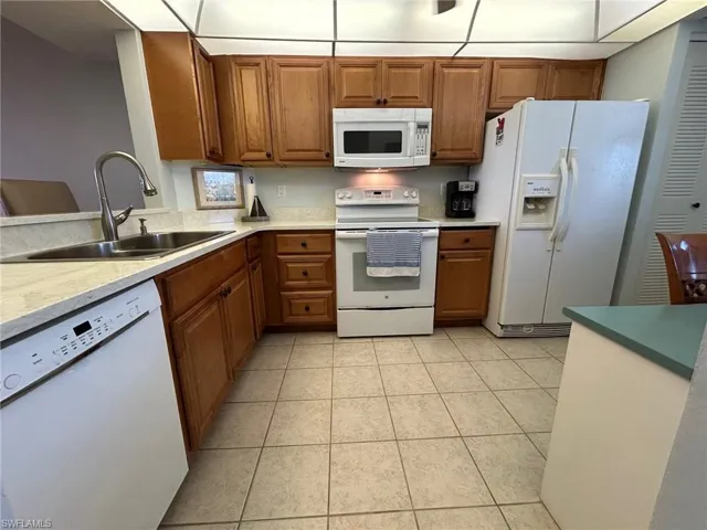 Kitchen with sink, white appliances, and light tile patterned floors
