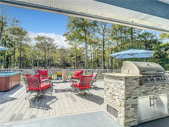 Wooden terrace with an outdoor kitchen, view of wooded area, and a hot tub