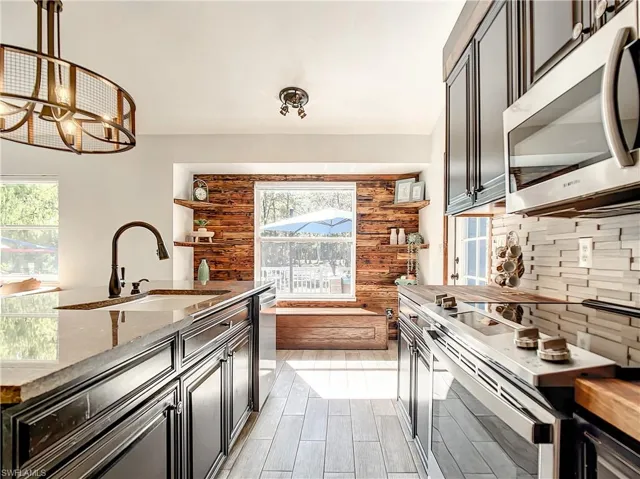 Kitchen featuring stainless steel appliances, butcher block countertops, backsplash, and a chandelier