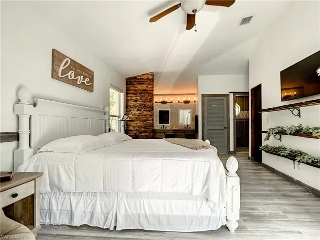 Bedroom with vaulted ceiling, light wood-type flooring, and a ceiling fan