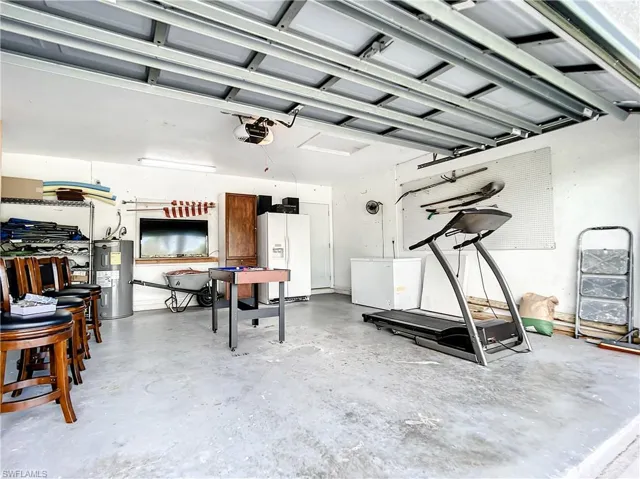 Garage featuring white refrigerator with ice dispenser, electric water heater, and white fridge