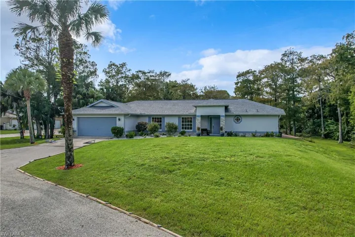 Ranch-style house with stucco siding, concrete driveway, and a front yard