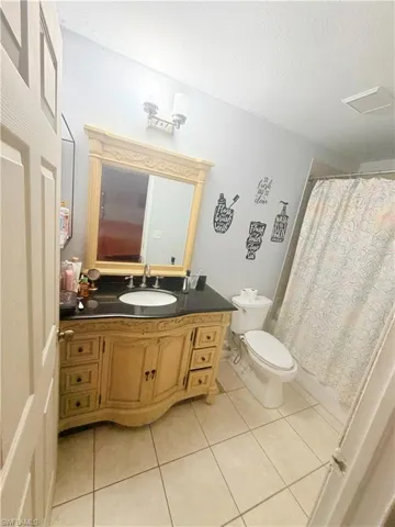 Vanity with carved wood-finish cabinetry, black countertop, and integrated sink