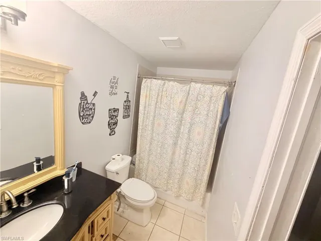 Vanity with wood-finish cabinetry, dark countertop, and gold-framed mirror