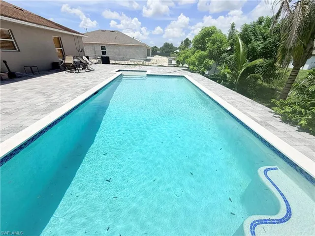 Rectangular inground pool with a tiled entry, surrounded by a paver patio