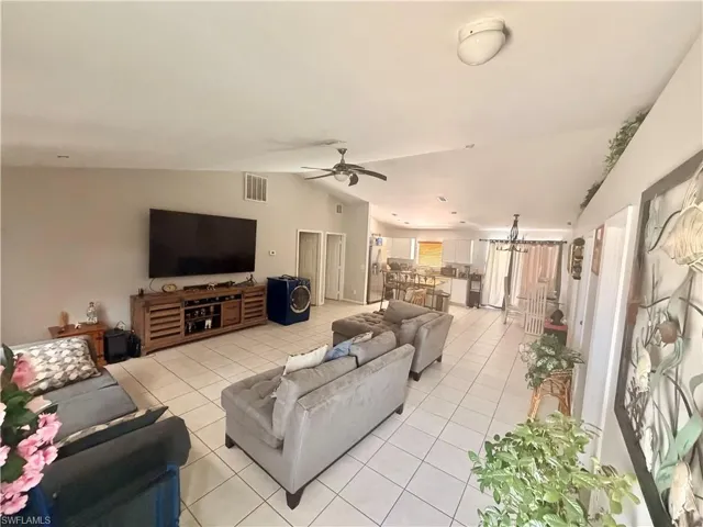 Spacious living area featuring tiled flooring, a vaulted ceiling, and a ceiling fan