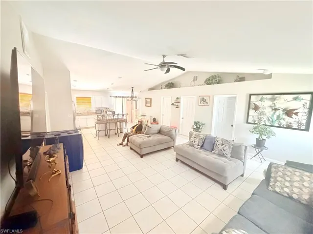Vaulted ceilings, white tile flooring, ceiling fan, and recessed display alcove
