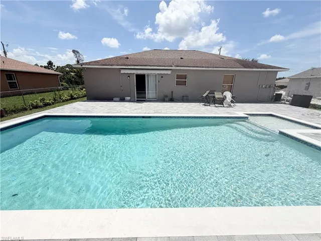 Backyard featuring a rectangular swimming pool with integrated spa, paver deck, and sliding glass door access to the interior