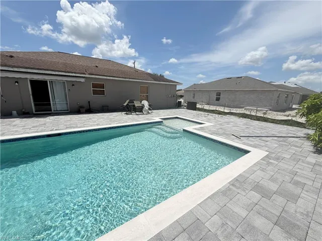 Private swimming pool with a step entry, surrounded by a paved patio, and a sliding glass door
