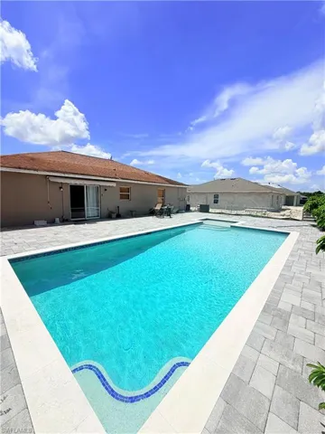 Rectangular swimming pool with tiled steps, surrounded by light gray paver decking