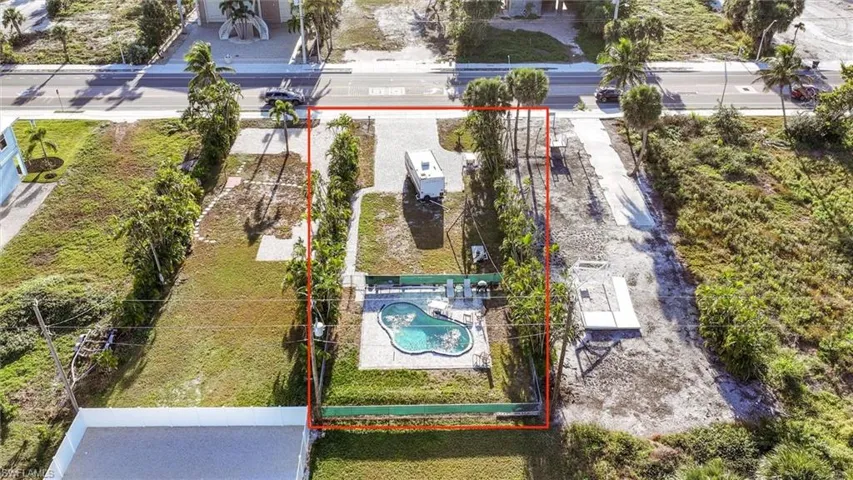 Aerial view of property and surrounding area featuring property parcel outlined and a pool area