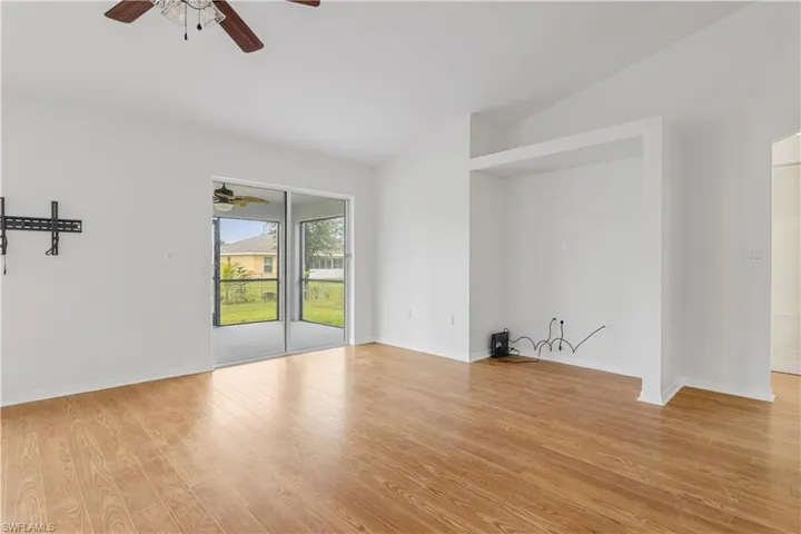 Great room with light wood-type flooring, lofted ceiling, and ceiling fan