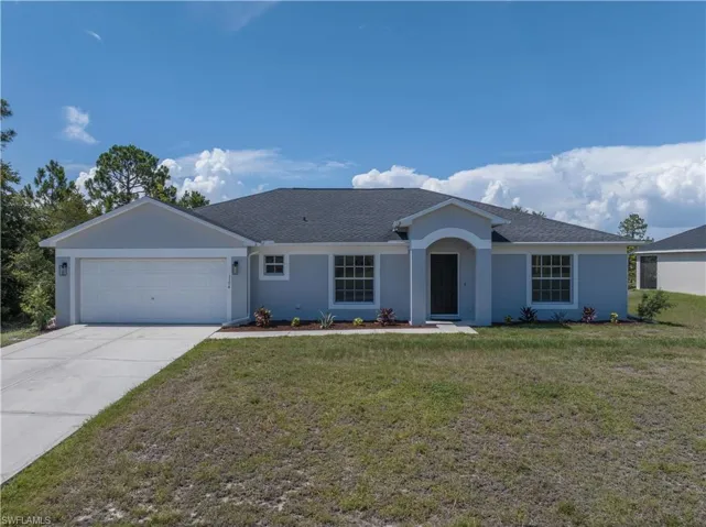Ranch-style house featuring a garage and a front lawn