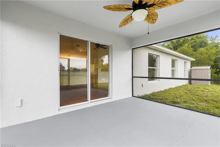 View of freshly painted screened lanai with ceiling fan and a shed