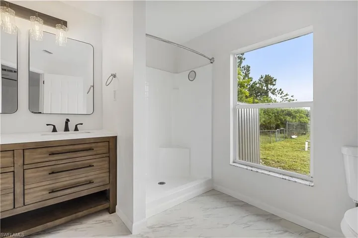 Bathroom with a shower, tile flooring, toilet, and vanity with extensive cabinet space