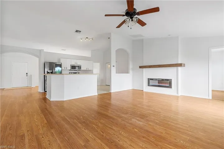 Unfurnished living room with light wood-type flooring and ceiling fan