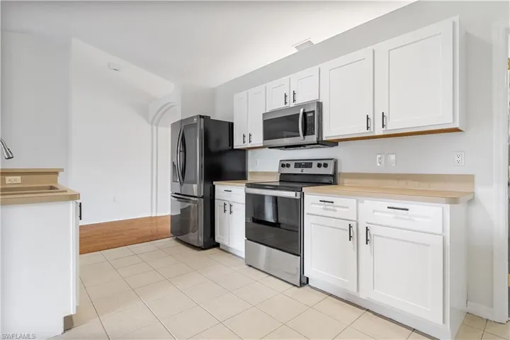 Kitchen with stainless steel appliances, white cabinets, light wood-type flooring, and sink
