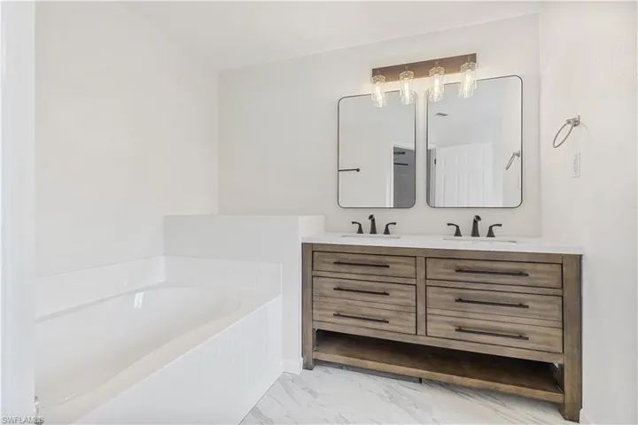 Bathroom featuring tile floors, a tub, oversized vanity, and dual sinks