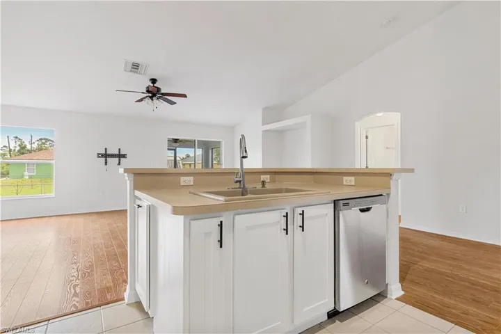 Kitchen featuring dishwasher, ceiling fan, white cabinetry, light wood-type flooring, and sink